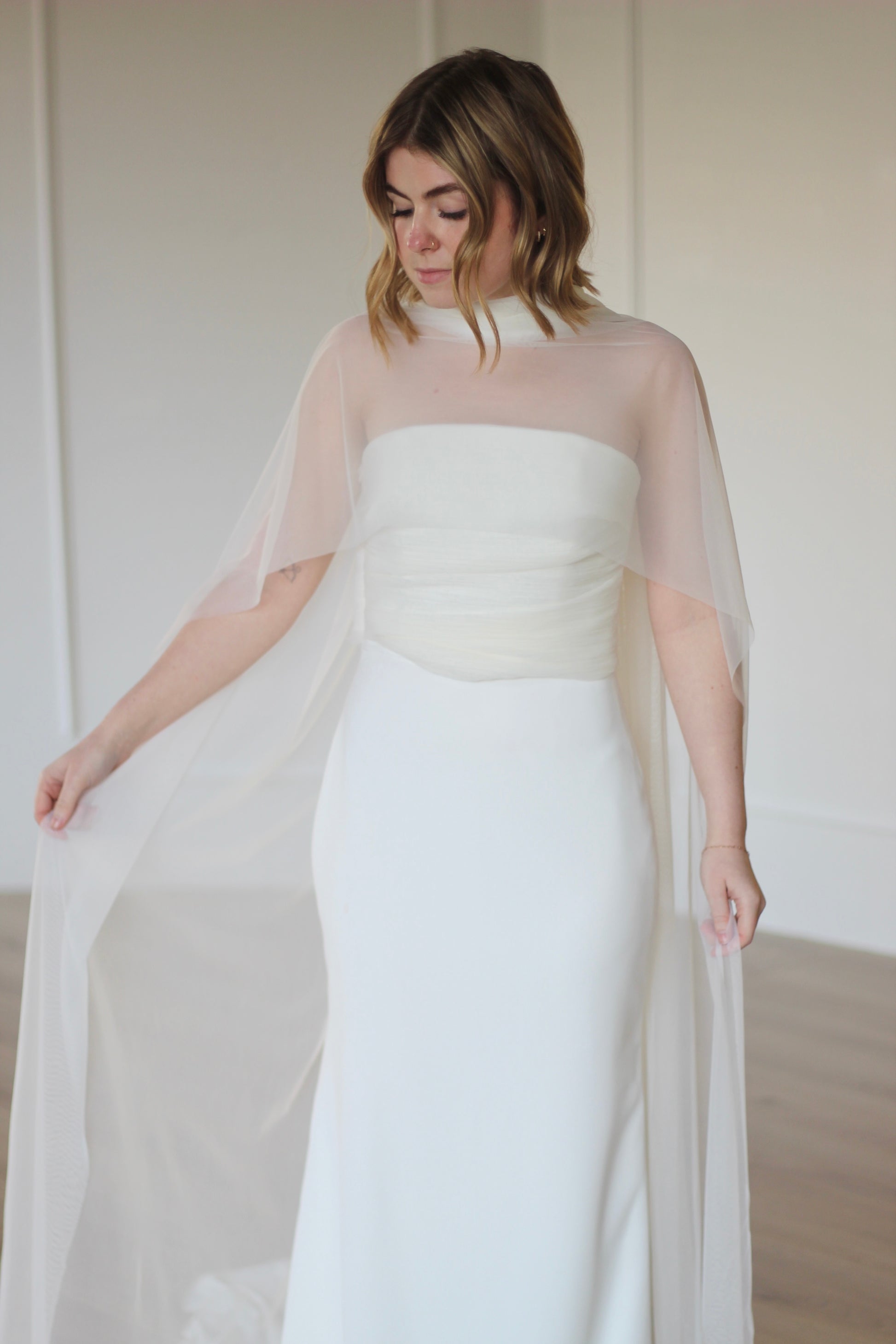 Sheer bridal capelet overlay paired over a strapless wedding dress