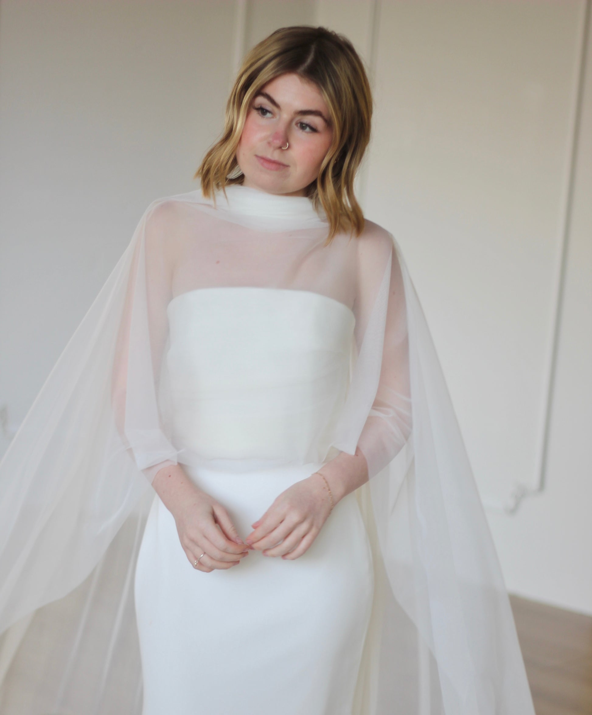 Woman wearing a white wedding dress with a sheer bridal shawl